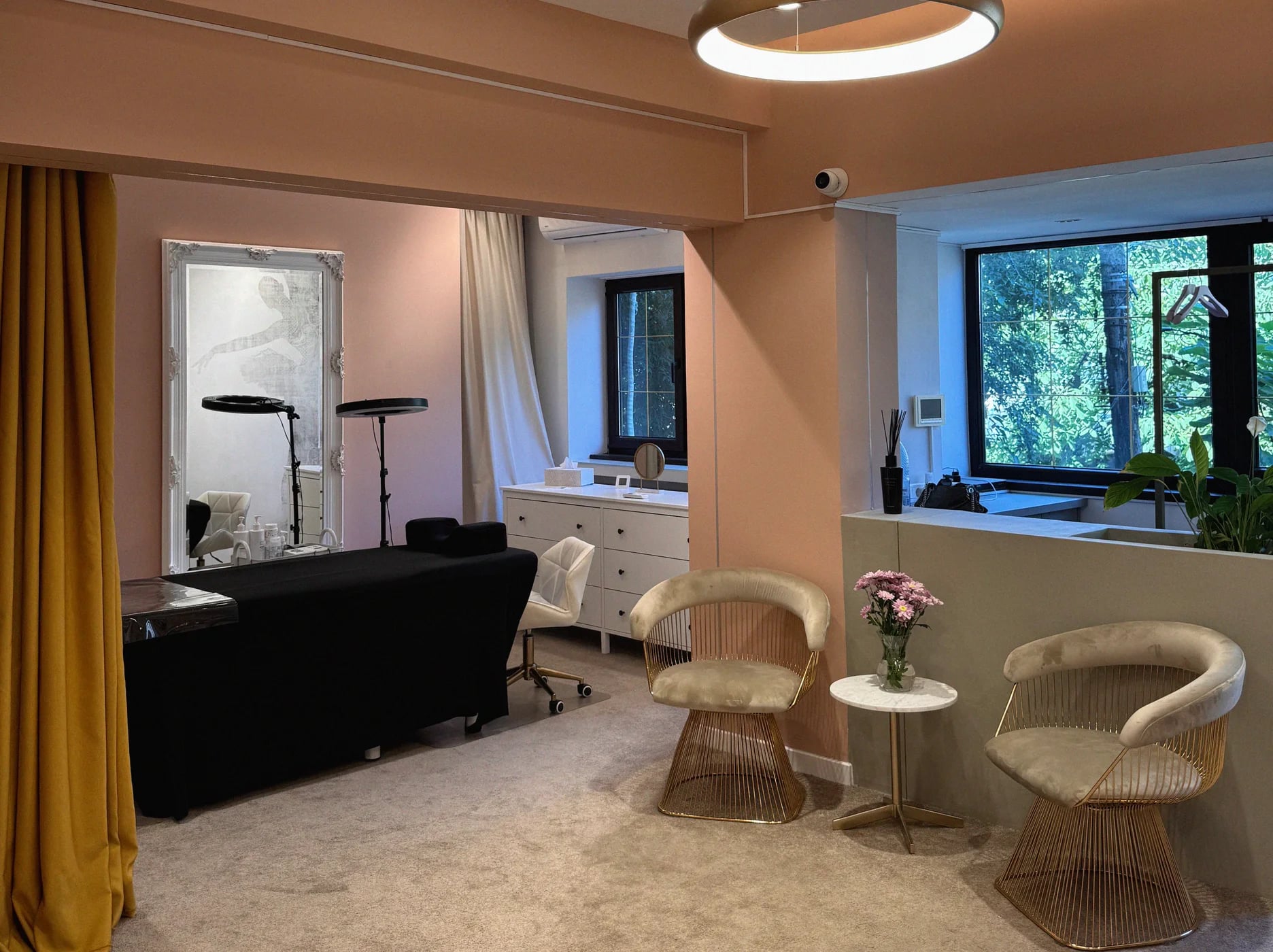 Zona de așteptare a salonului Perfect Pulse: canapea neagră, fotolii din ratan, draperii aurii și ferestre mari