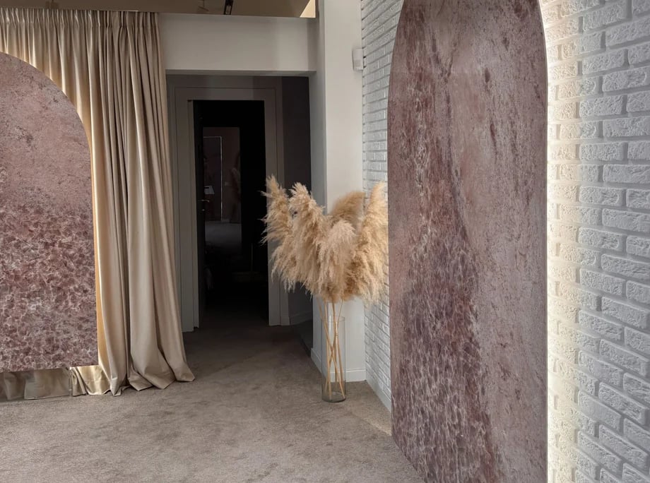 Detaliu din salon: perete cu textură de marmură, draperie bej și pampas într-o vază